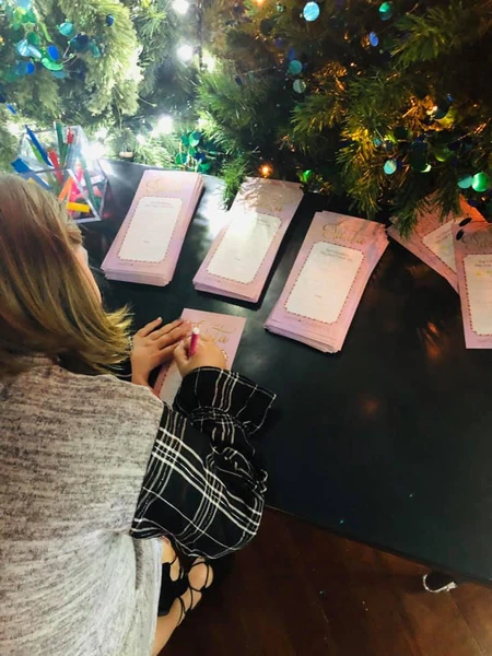 Harper writing her Christmas wish list to Santa under twinkling holiday lights at Smith & Caughey’s in Auckland, New Zealand.