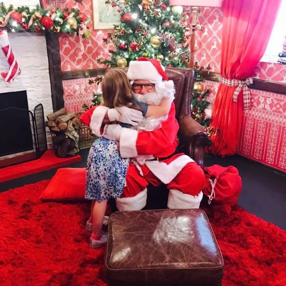 Harper gives Santa a big hug in a festive Christmas setting at Smith & Caughey’s Santa Experience in Auckland, New Zealand.