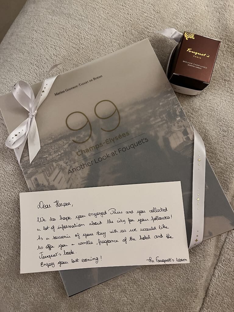 Thoughtful guest gift from Le Fouquet’s Paris including a beautifully packaged history book and signature candle, reflecting the hotel’s elegant hospitality and Parisian heritage