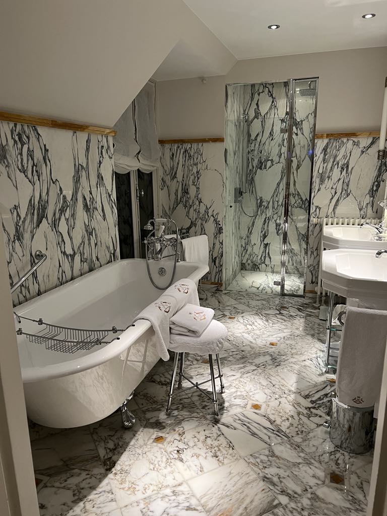 Elegant marble bathroom with grey and white finishes, featuring a deep soaking tub and upscale amenities—perfect for relaxation in a luxury hotel suite.