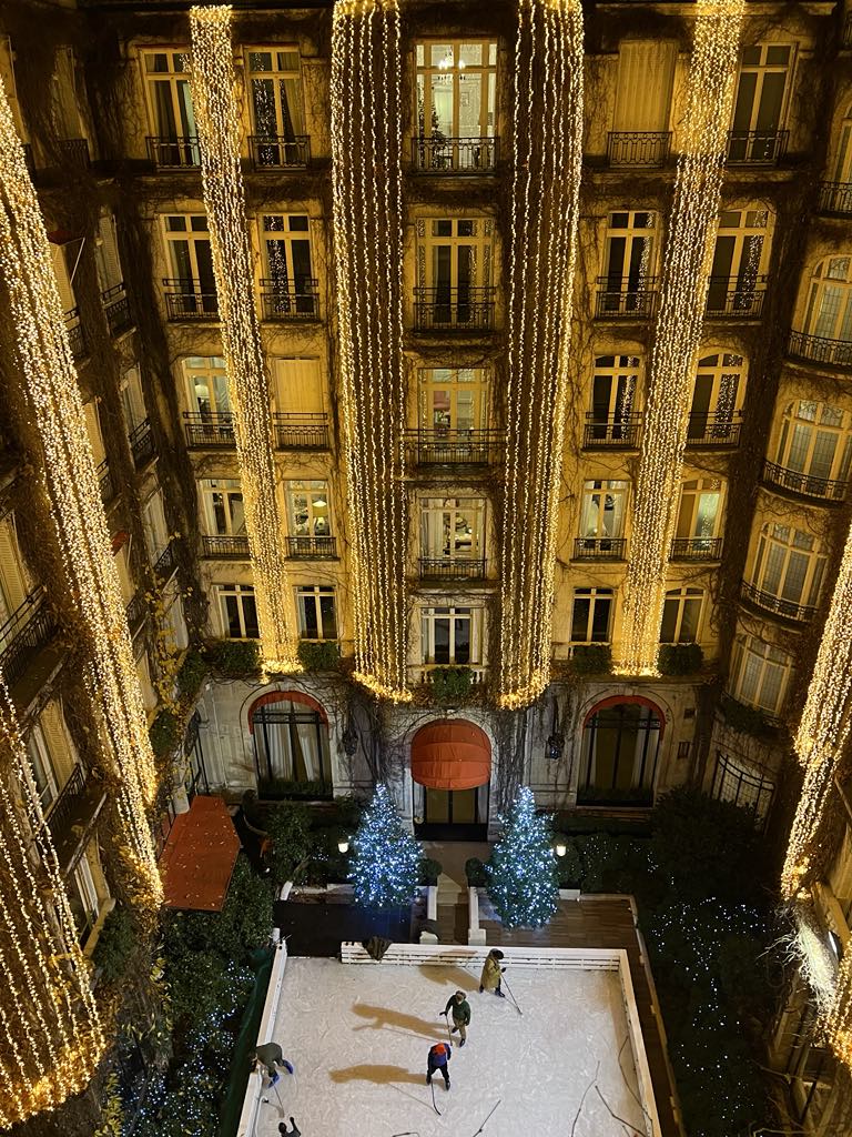 Magical winter courtyard at Hôtel Plaza Athénée in Paris with a festive ice skating rink, offering guests a luxurious and family-friendly holiday experience in the heart of Avenue Montaigne.