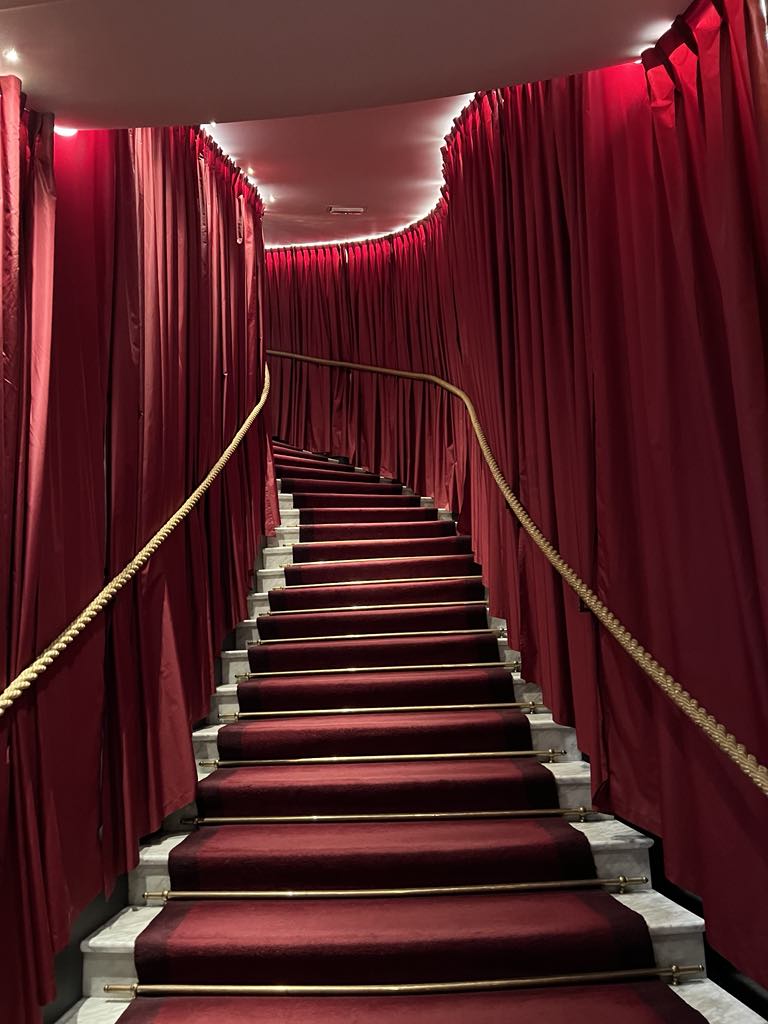 Luxurious Hollywood glam staircase featuring sweeping curves, rich textures, and vintage-inspired lighting—perfect for stylish entrances and red carpet moments at a luxury hotel or event venue.