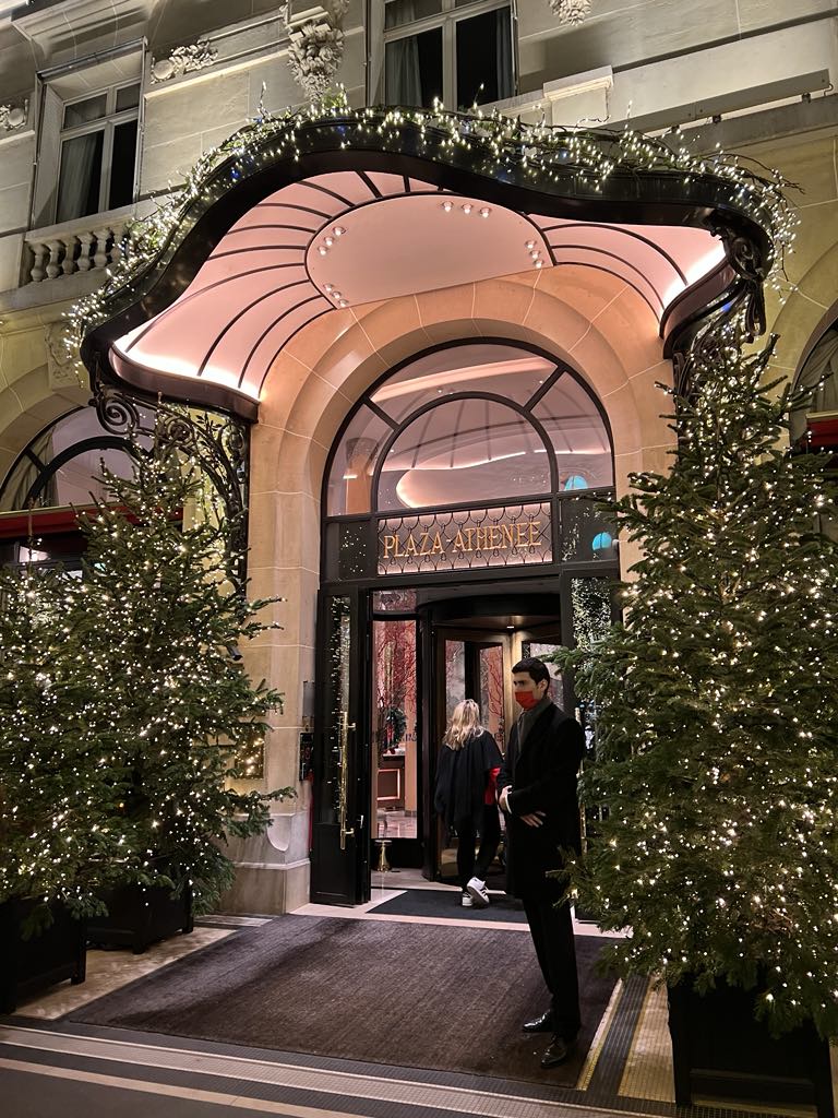 Iconic façade of Hôtel Plaza Athénée in Paris, showcasing classic Parisian architecture with signature red awnings, wrought-iron balconies, and luxurious charm on Avenue Montaigne.