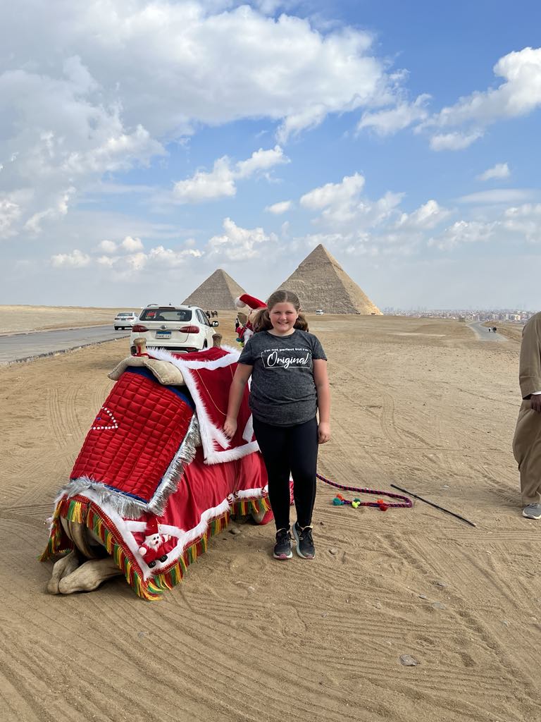 girl standing next to camel in cairo egypt