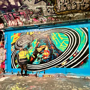 Street artist creating vibrant graffiti inside London’s Leake Street Tunnel, a popular spot for urban art and creative expression.