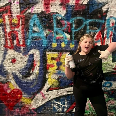 Teen traveler creating street art in London’s Leake Street Tunnel, experiencing hands-on urban culture during a family adventure.