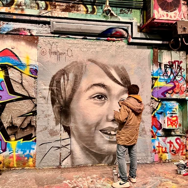Street artist creating vibrant graffiti inside London’s Leake Street Tunnel, a popular spot for urban art and creative expression.