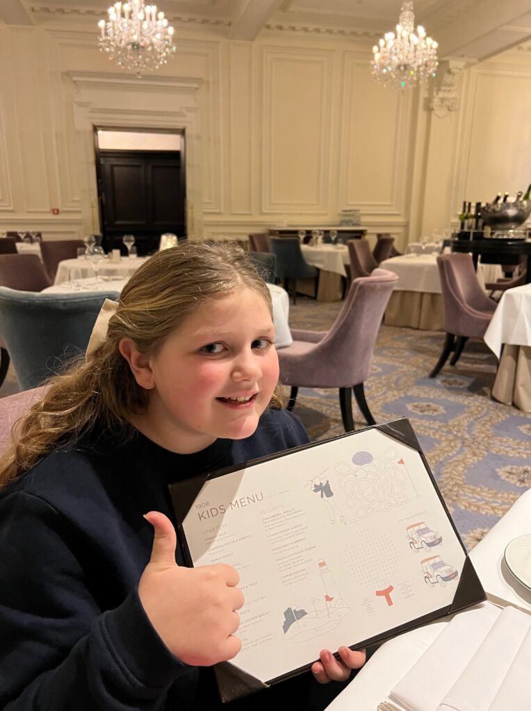 Harper giving a thumbs up while holding a kids’ menu at the elegant 1906 Restaurant inside Trump Turnberry, Scotland. Harper's Touch
