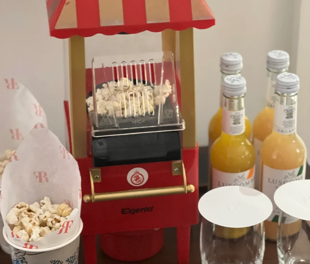 Vintage-style red popcorn machine with Luscombe organic juices and popcorn cups at a luxury hotel snack station.