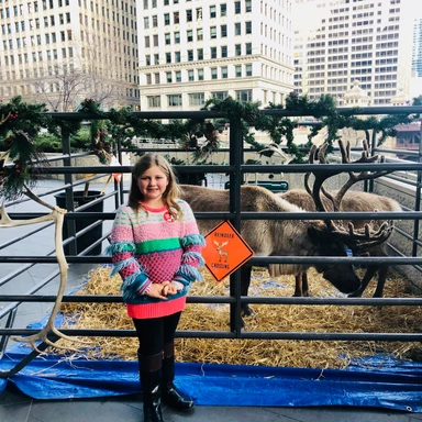 kid traveler Harper standing next to a reindeer during a magical holiday experience, enjoying festive family fun at a luxury destination.