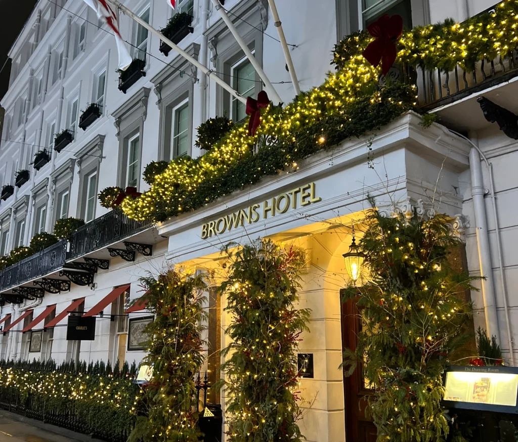 Exterior view of The Brown’s Hotel in London decorated with elegant Christmas lights and garlands at night.