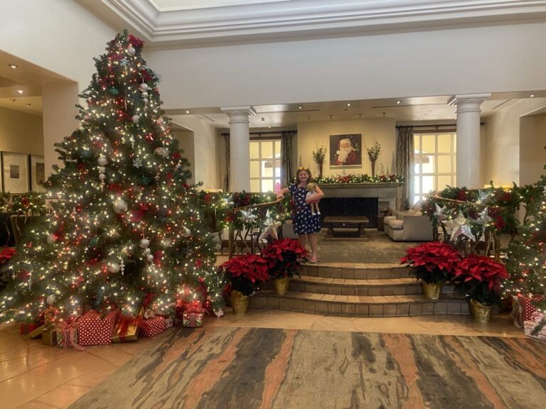 kid traveler Harper standing in the festive lobby of the Fairmont Scottsdale Princess, surrounded by dazzling holiday decor during the “Christmas at the Princess” luxury family celebration.