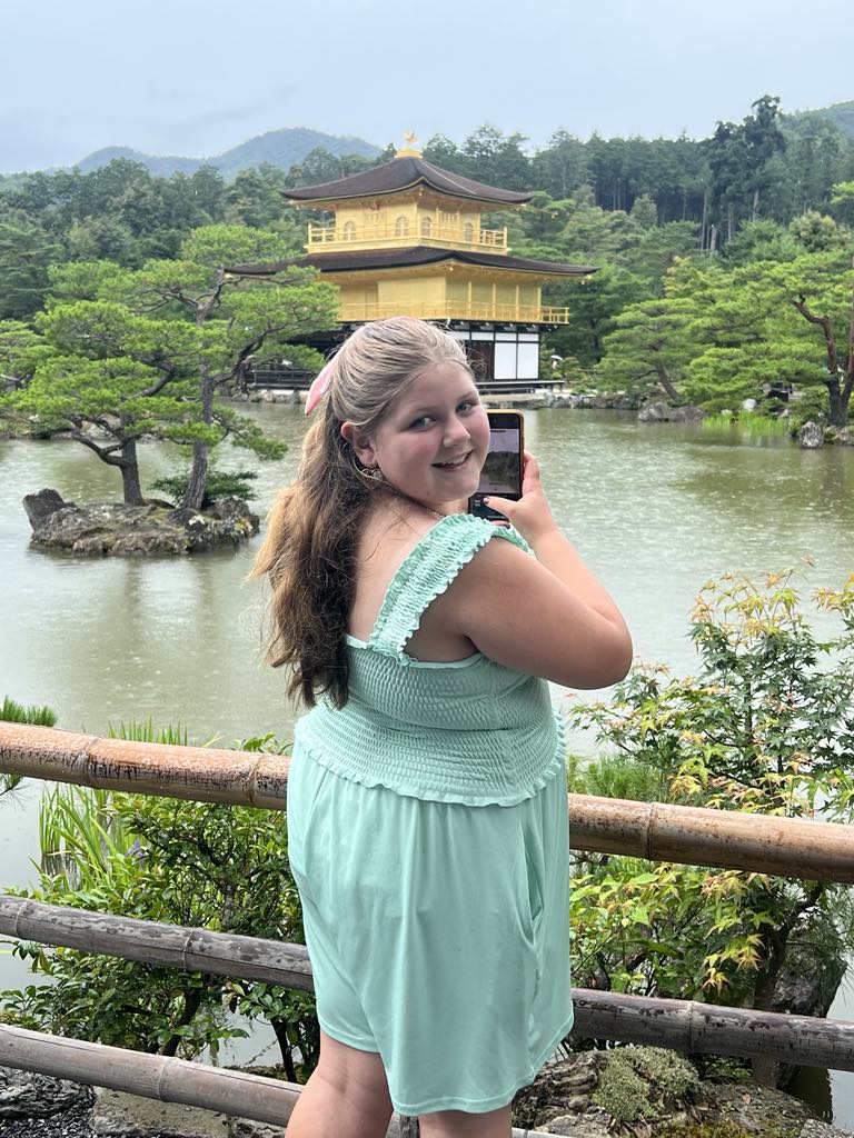 Teen traveler Harper photographing Kyoto’s iconic Golden Temple, Kinkaku-ji, capturing the beauty of Japan’s historic landmark during a cultural family adventure.
