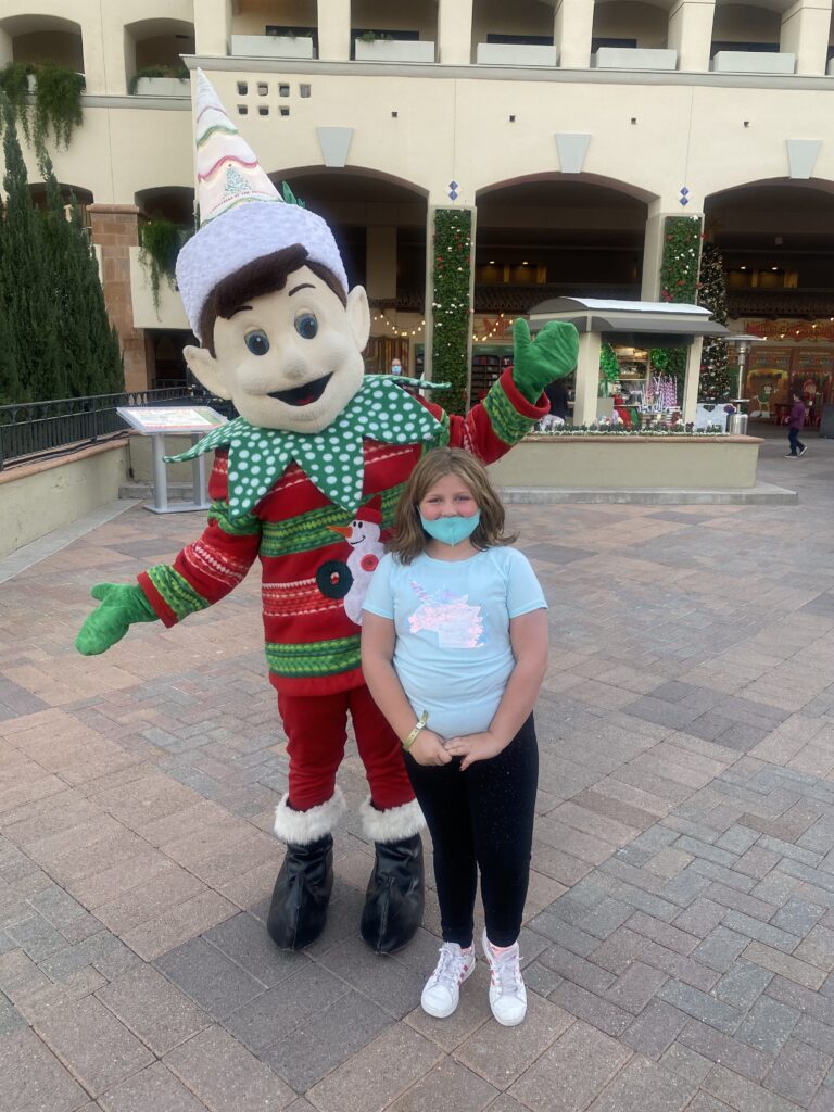 traveler Harper smiling with holiday characters at the Fairmont Scottsdale Princess, enjoying the festive magic of the “Christmas at the Princess” family event.