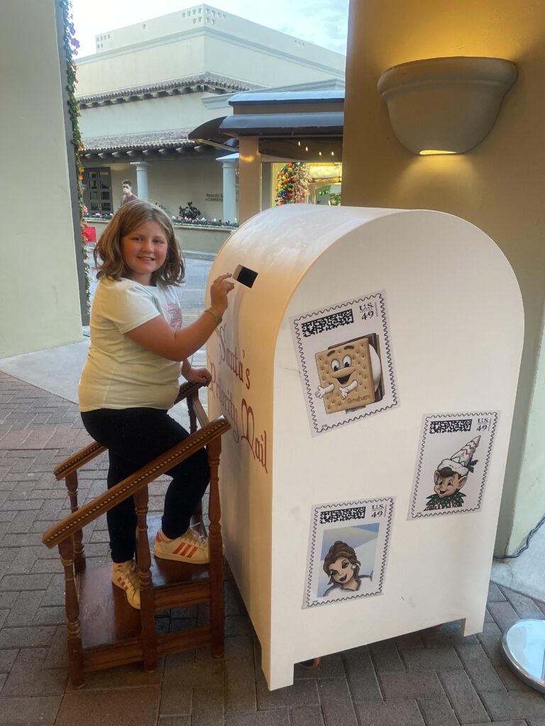 traveler Harper mailing her letter to Santa in a whimsical holiday mailbox at the Fairmont Scottsdale Princess during the “Christmas at the Princess” celebration.