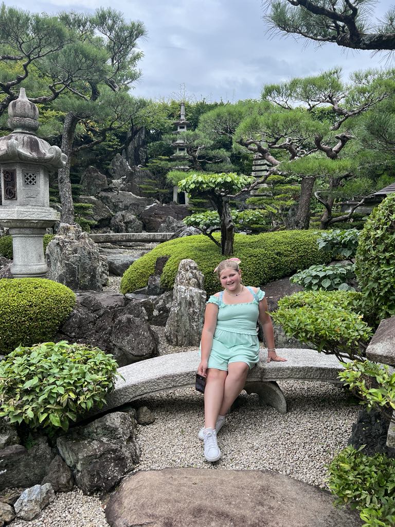 Teen traveler Harper posing in a serene Japanese Zen garden in Kyoto, experiencing cultural beauty and mindfulness during a luxury family journey through Japan.