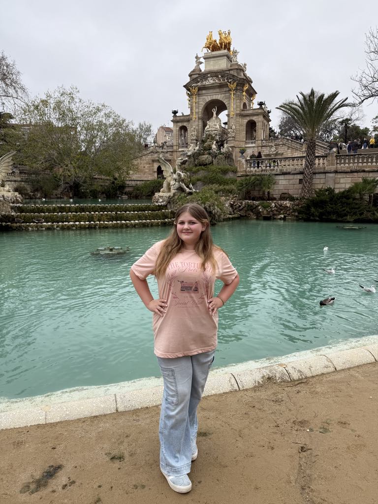 Harper standing in front of the grand Cascada Monumental fountain in Ciutadella Park, Barcelona, Spain, wearing a stylish outfit and smiling—capturing a perfect luxury family travel moment in Harper’s World.