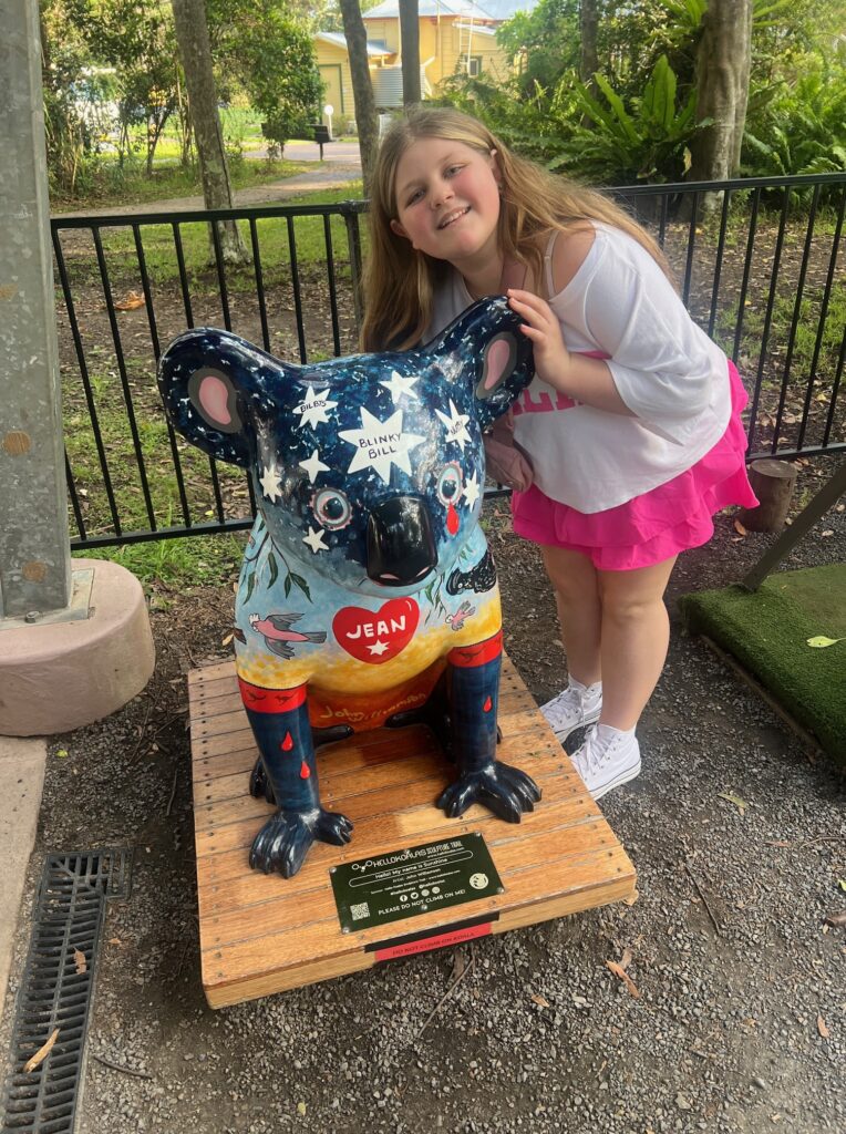 Girl standing with hello koala statue