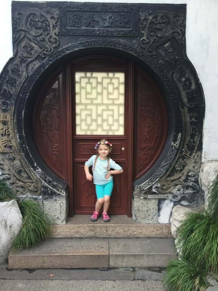 Harper as a young child standing in front of an ornate circular doorway in China