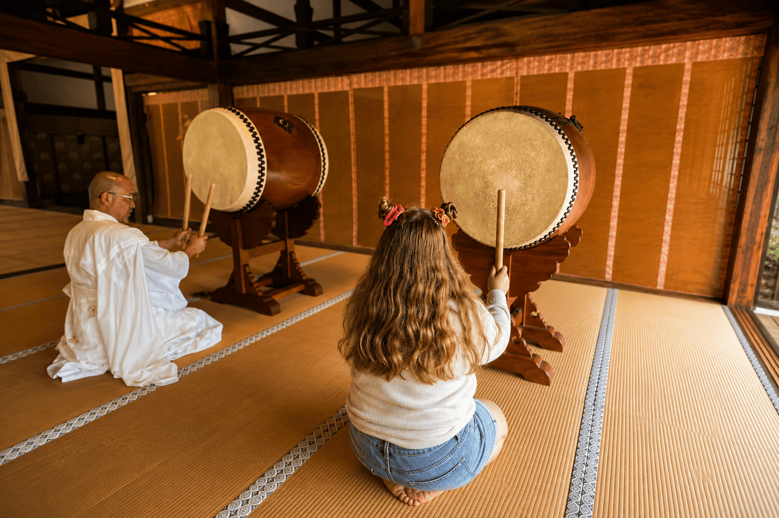 Harper learning traditional drumming alongside a Buddhist instructor
